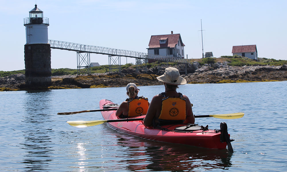 A couple in a tandem kayak at Ram Island Lighthouse, Boothbay Harbor, Maine